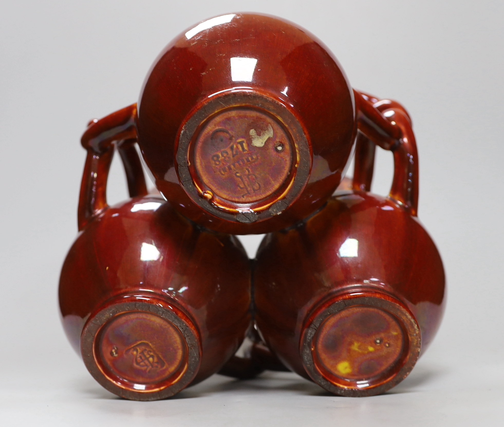 A Burmantofts Pottery three section fuddling cup with interwoven handles in dark burnt orange, stamped with marks to base, height 21cm